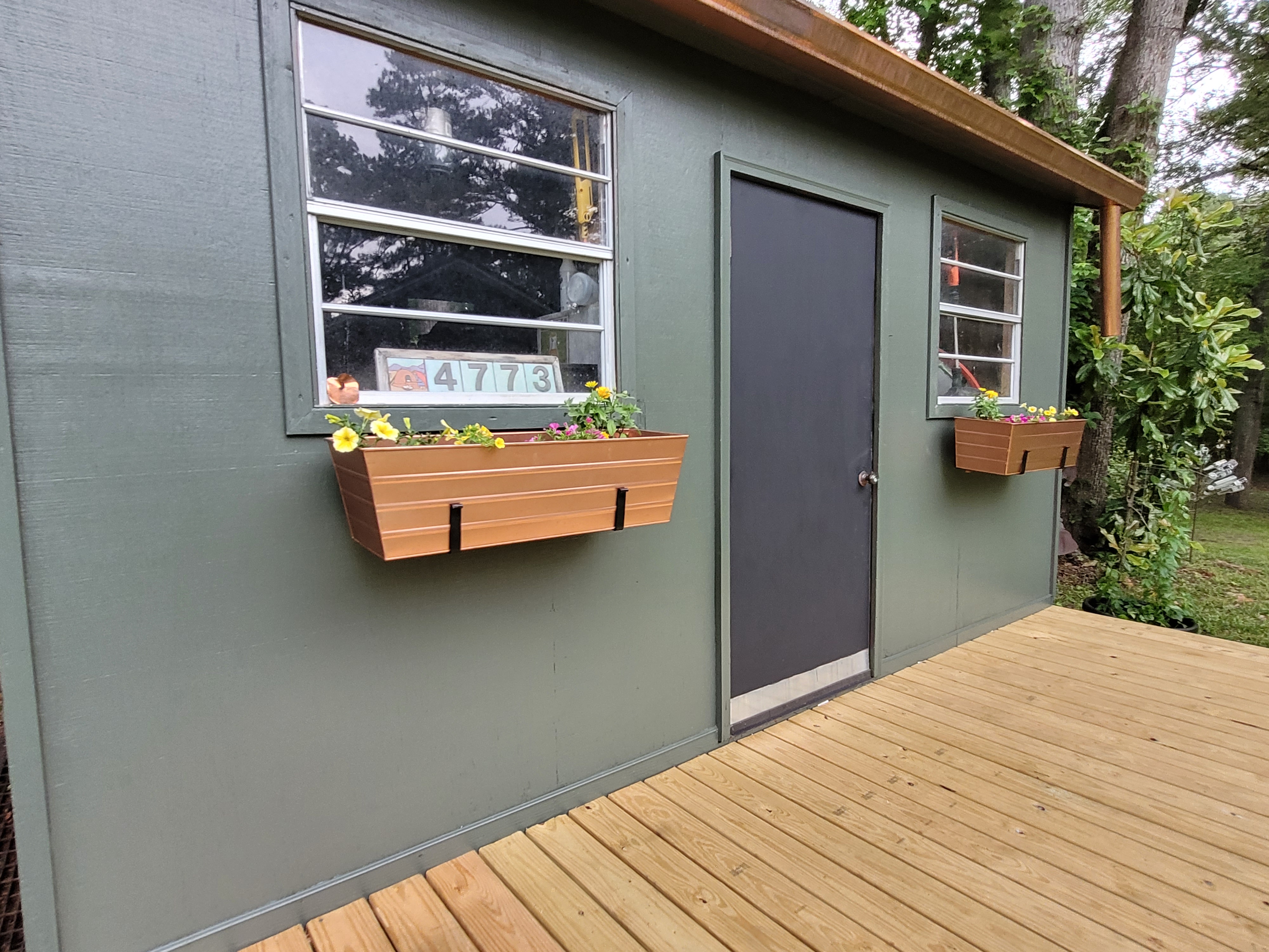 Tool shed with flower boxes, paint, and wooden deck